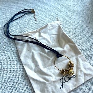 J. Crew necklace with a black waxed rope and gold ring with metal balls.